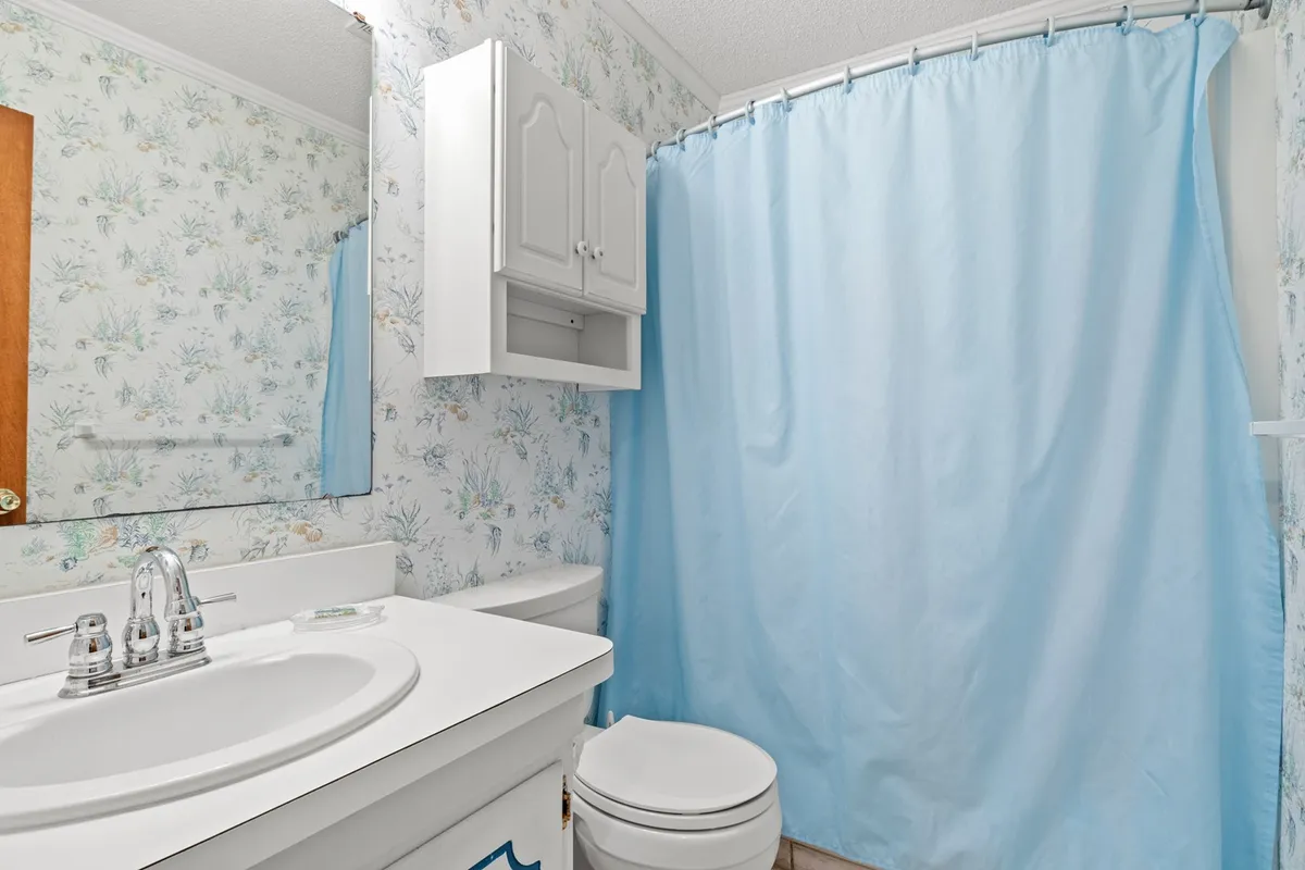 The image captures a tidy interior laundry area with a sink, mirror, and shower curtain visible, suggesting facilities for self-care and daily routines. While not a traditional laundry room, it visually aligns with the 'convenient extras' and necessary amenities theme.