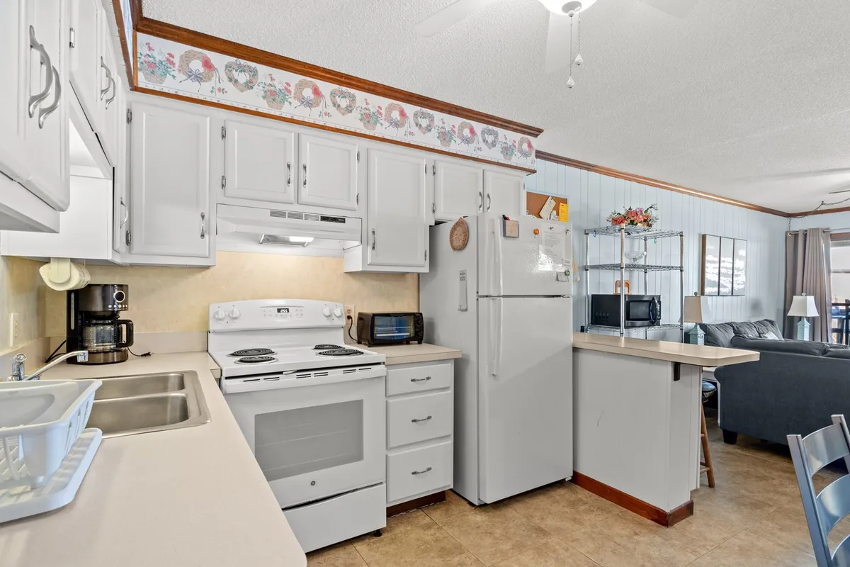 A cozy, welcoming kitchen scene featuring modern appliances, spacious countertops, and a window that lets in natural light. The dining area is visible, making it clear that this is a combined space ideal for meal prep and gathering.