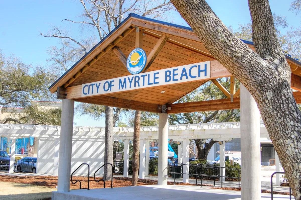 This image features an inviting pavilion structure with the 'City of Myrtle Beach' sign, surrounded by lush trees and benches. The area is designed for community events, gatherings, and leisurely activities, offering a glimpse of the neighborhood's social and welcoming atmosphere.
